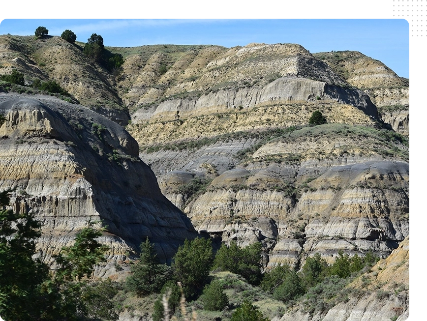 A large rock formation with trees in the foreground.