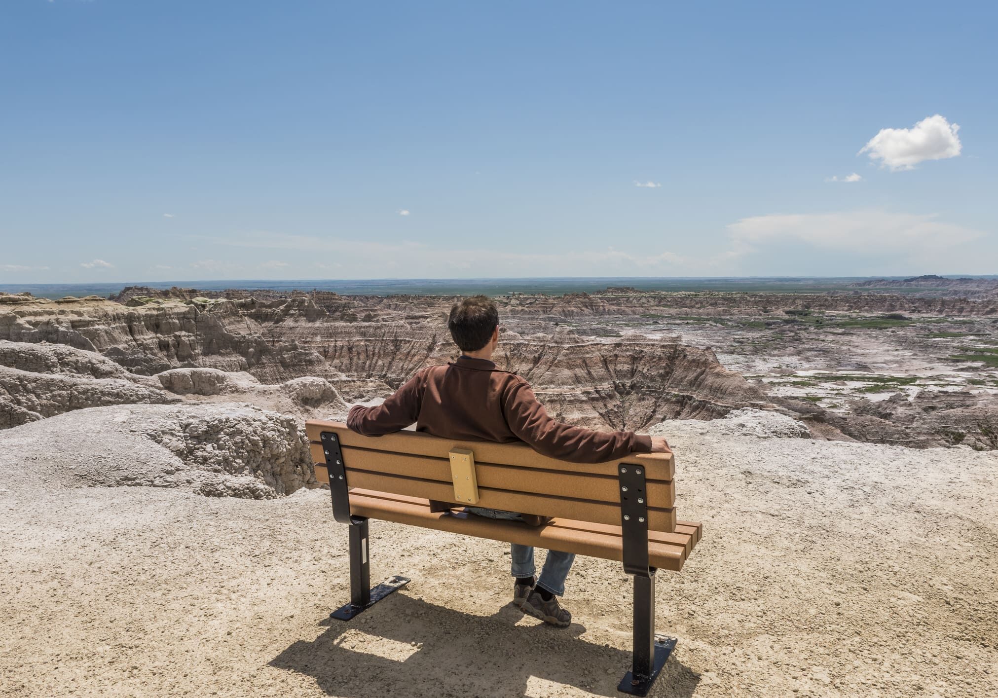 A man sitting on top of a wooden bench.